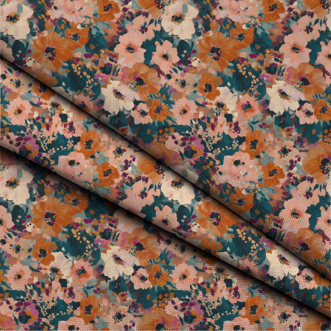 A close-up of floral fabric with a dense multicolor print featuring orange, pink, teal, cream, and purple flowers on a textured woven background, with one folded section showing the material's drape.