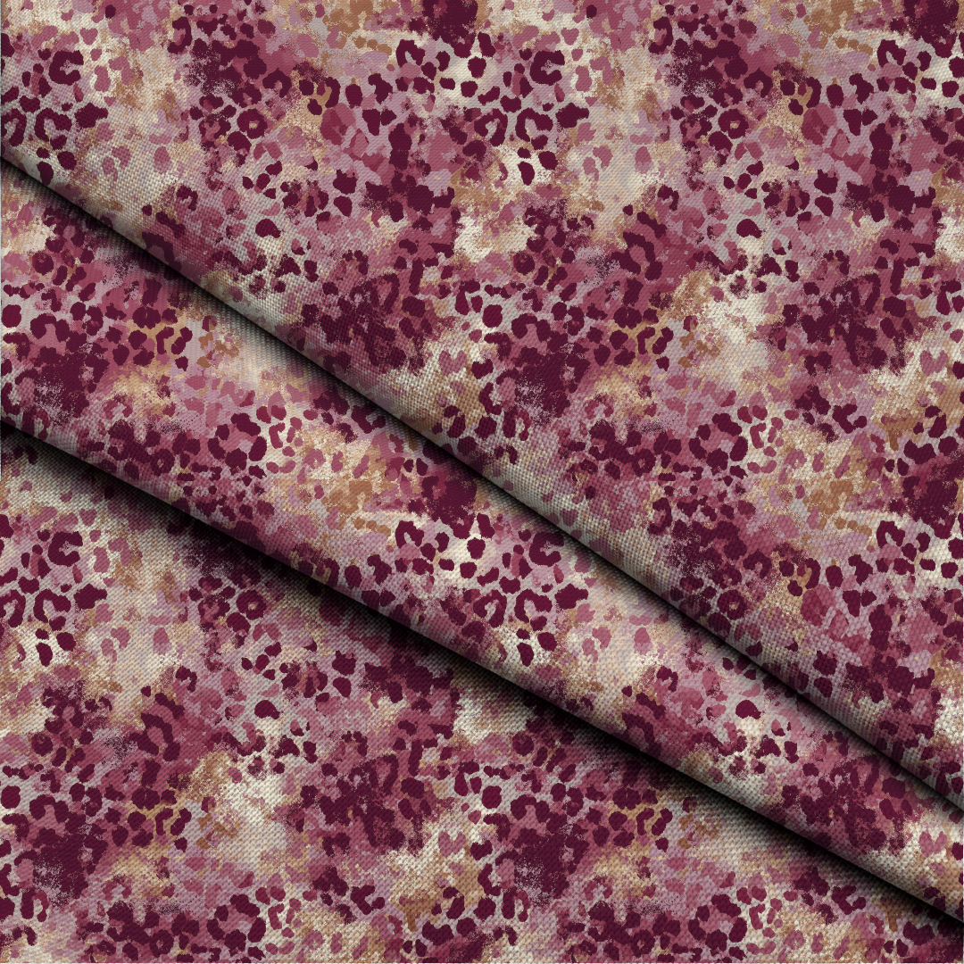 A close-up of patterned fabric with a dense abstract print in deep burgundy, mauve, dusty rose, and beige, folded diagonally across the frame.